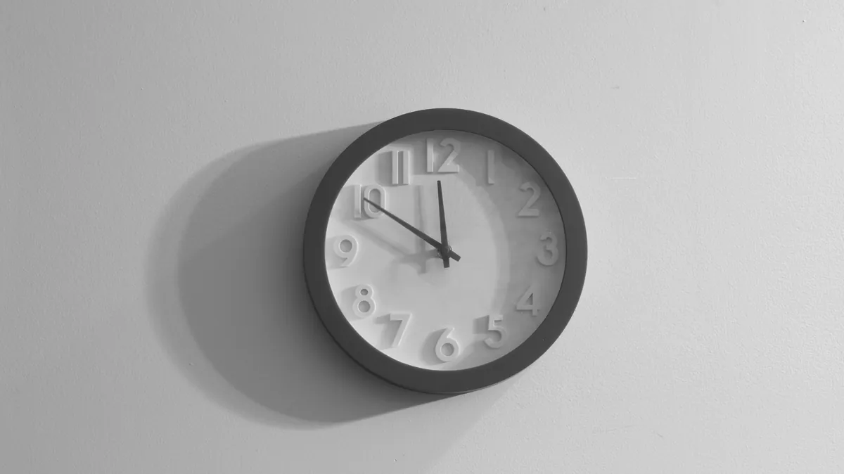 Primeiro plano do mostrador de um relógio analógico com os ponteiros das horas e dos minutos